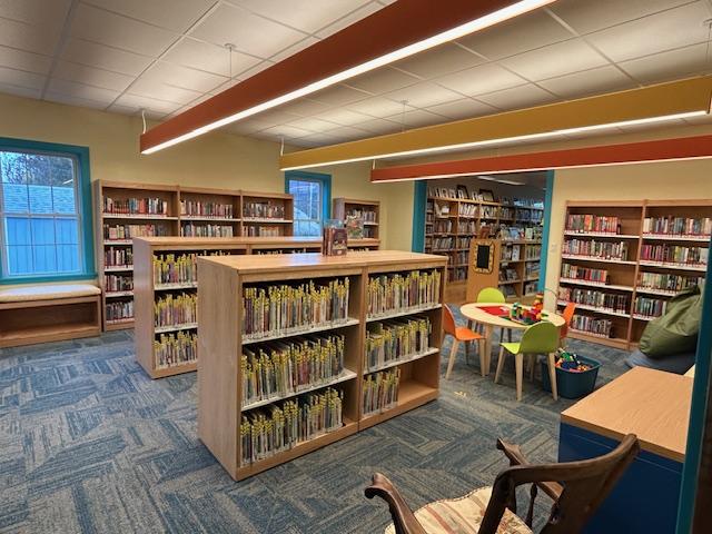 Children's room with blue carpet, yellow walls, orange and yellow lights, bookcases.